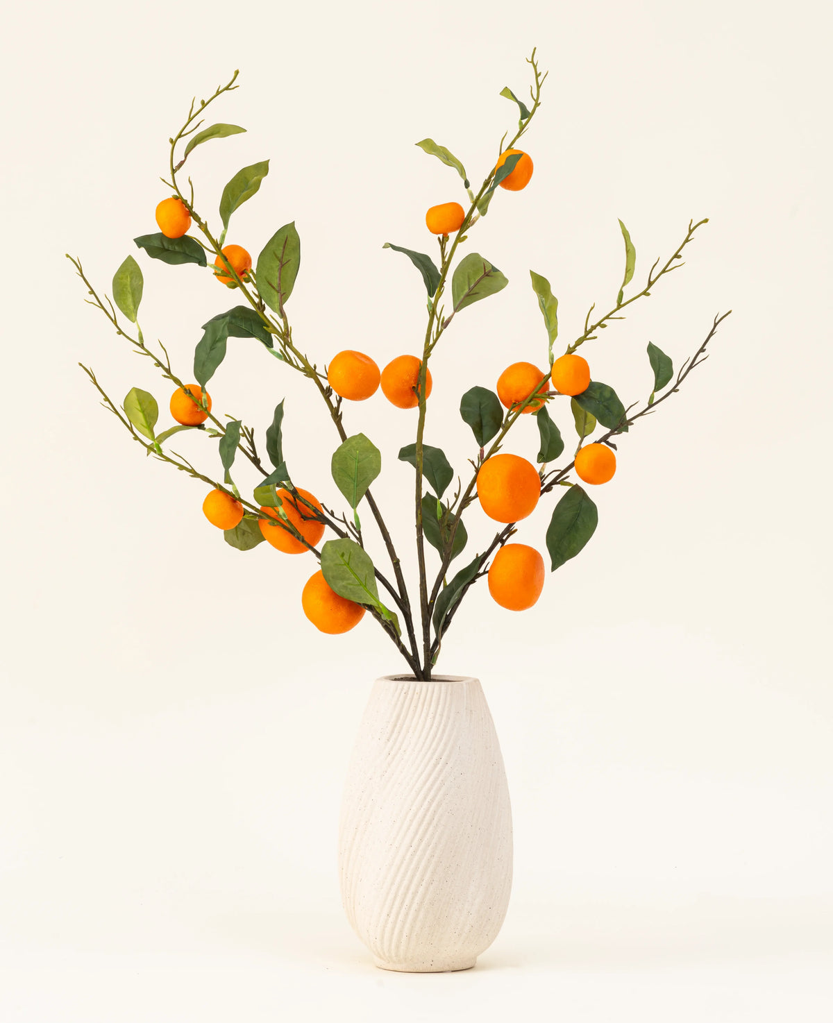 Het Zijden kunstbloemen boeket Mandarijn heeft een vaas met witte textuur en takken van groene bladeren en levendige oranje kunstmandarijnen, die een levendige toets geven tegen een effen lichte achtergrond.