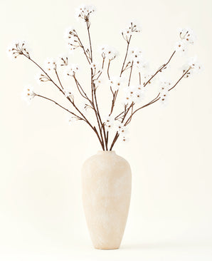Het Zijden kunstbloemen boeket Kersenbloesem crème 114 cm staat hoog in een beige keramische vaas en brengt een serene decoratie in elke ruimte met zijn delicate, crèmekleurige takken tegen een lichte achtergrond.